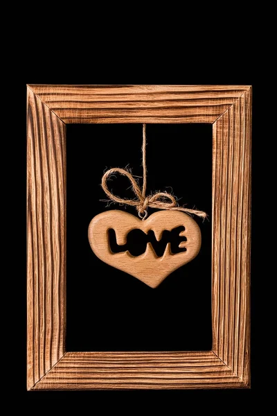 Heart hanging in old picture frame  on black background — Stock Photo, Image