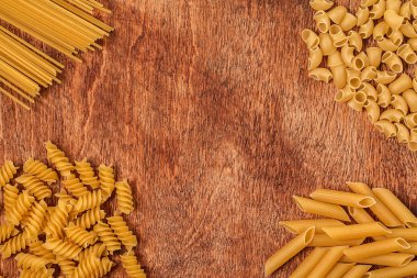 Ahşap arka plan üzerinde farklı şekil makarna çeşitleri