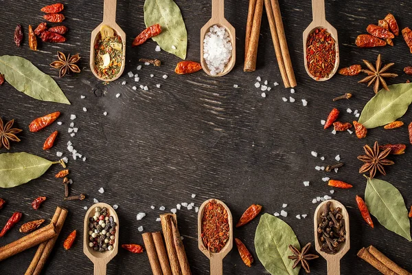 Various spices in wooden spoons  on dark wooden table