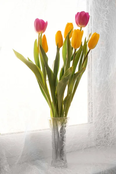 Un ramo de tulipanes en un jarrón en el alféizar de la ventana —  Fotos de Stock