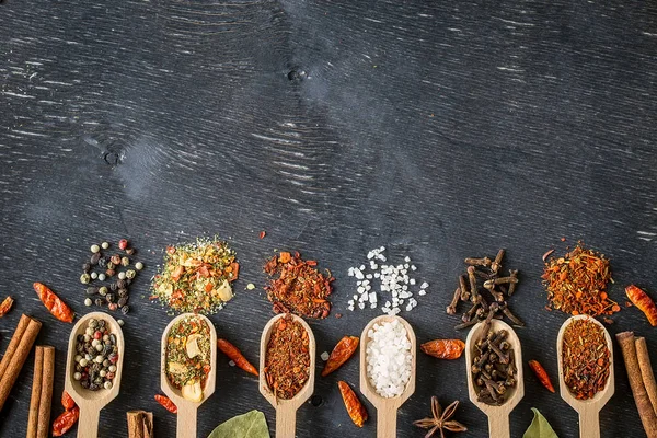 Various spices in wooden spoons  on dark wooden table — Stock Photo, Image