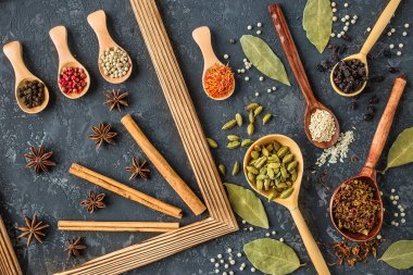 Tahta kaşıklar karanlık taş tablo içinde çeşitli baharatlar
