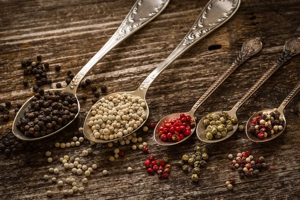 Schwarze und weiße Paprika auf altem Holztisch. Stockbild