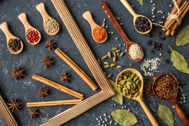 Tahta kaşıklar karanlık taş tablo içinde çeşitli baharatlar