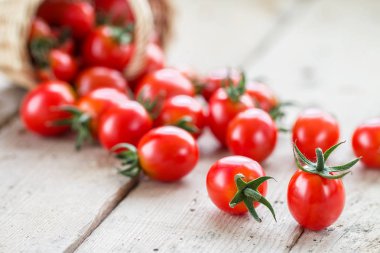 Küçük kırmızı kiraz domates bir hasır sepet dışarı dökmek 
