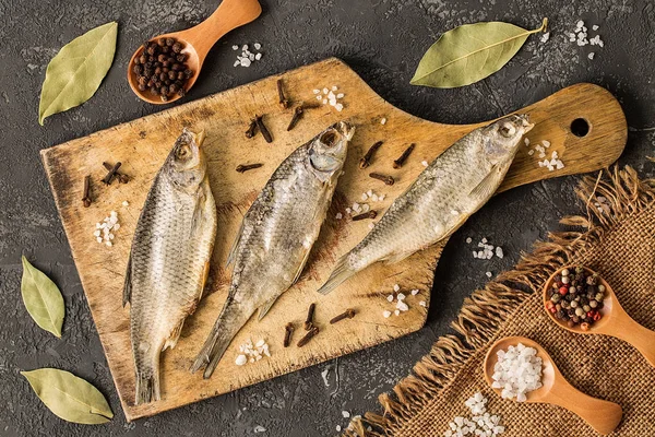 Dried fish with salt and pepper on cutting board — Stock Photo, Image