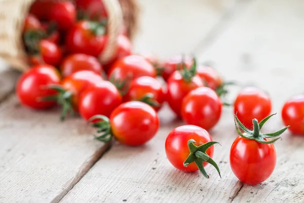 Küçük kırmızı kiraz domates bir hasır sepet dışarı dökmek 