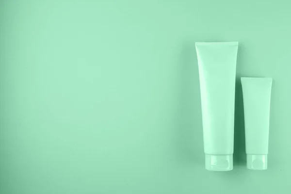 Two cosmetic tubes package on mint color background.