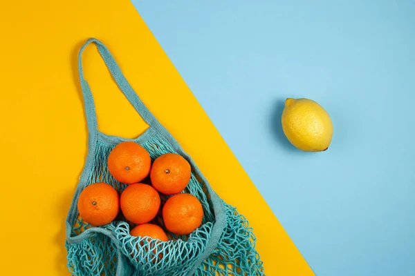 Mesh textile bag full of colorful fruit. Healthy food and zero waste concept