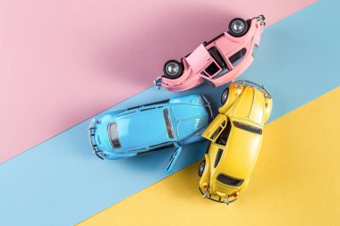 Pastel renkli arka planda kazara oyuncak arabalar. Üç araba kazası, araba kazası sigortası. Yarış pistinde yarış arabaları.