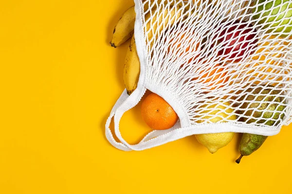 Zero waste plastic free concept. Fresh fruit in a mesh net bag, top view with copyspace. Mesh shopping bag with fruits. Sustainable lifestyle