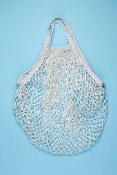 青い紙の背景に白い綿のメッシュバッグ 再利用可能なショッピングバッグ上の色背景 生態学的廃棄物ゼロの概念 トップビュー フラットレイアウト コピースペース — ストック写真