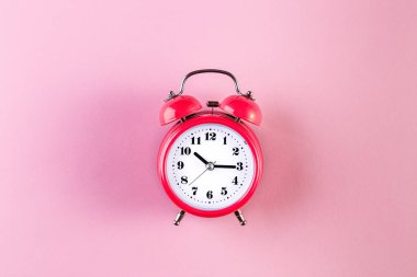 Açık pembe arka planda kırmızı klasik alarm saati. Zaman yönetimi kavramı