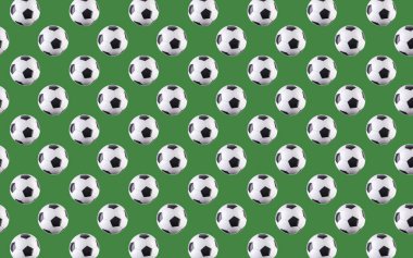 Topların kusursuz deseni. Havada uçuşan siyah ve beyaz futbol topları, yeşil arka planda izole edilmiş. Minimalist spor anlayışı