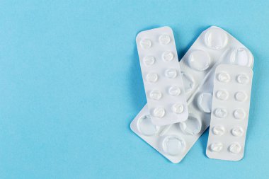 Mavi arka planda kullanılmış bir yığın hap. Tıbbî kabarcıklar haplar olmadan açıldı ve boşaldı. Tıbbi ve sağlık hizmeti kavramı.