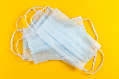 Koronavirüsü önle. Sarı arka planda tıbbi koruyucu maske. Corona koruması.