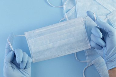 Tıbbi maskeler. Doktor, mavi arka planda mavi tıbbi eldiven elinde solunum maskesi tutuyor. Sağlık sigortası Coronavirus karantinası, hijyen konsepti