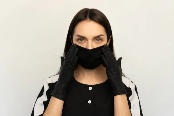 Coronavirus, uma jovem com uma máscara protetora preta e luvas pretas, vestida com roupas pretas — Fotografia de Stock