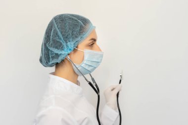 Elinde steteskopla koruyucu bir tıbbi maske takan bir doktoru kelepçele.
