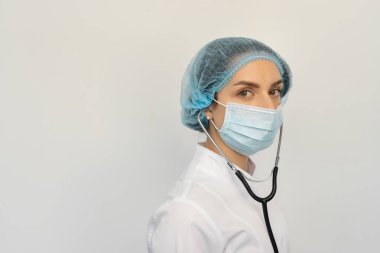 Elinde steteskopla koruyucu bir tıbbi maske takan bir doktoru kelepçele.