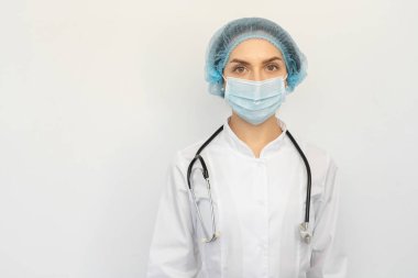Elinde steteskopla koruyucu bir maske takan bir doktor.