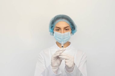 Koruyucu tıbbi maskeli ve şırıngalı eldivenli bir kadın doktor.