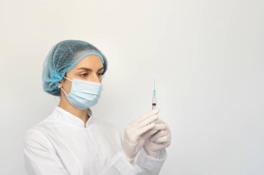 Koruyucu tıbbi maskeli ve şırıngalı eldivenli bir kadın doktor.
