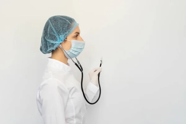 Een arts met een beschermend medisch masker met een stethoscoop in zijn handen — Stockfoto