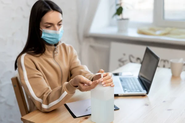 Koruyucu tıbbi maske takan genç bir kız COVID-19 karantinası sırasında dezenfektan dağıtıyor..