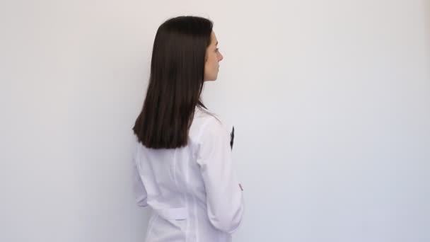 Amistosa doctora sonriendo sosteniendo una carpeta en sus manos, un estetoscopio en su cuello — Vídeos de Stock