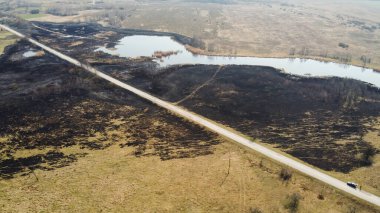 Orman ve arazi yangını. Kuru çimen yanıkları, doğal afet. Hava görüntüsü. Yangından sonra, zemin siyah bir yanık ve kül tabakasıyla kaplanır. Yangın sonrası duman tarlası