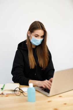 Evde çalışan genç bir iş kadını koruyucu maske takıyor, Coronavirus karantinası covid-19