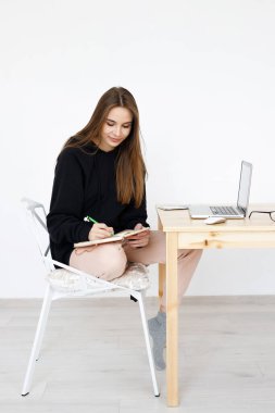 Çevrimiçi dersler sırasında dil öğrenmekten mutlu olan zeki genç bir kadın, elinde defterle gülümseyen bir öğrenci, ödevini yapıyor, bir blogcu internetten bilgi arıyor.