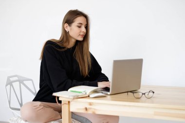 Çevrimiçi dersler sırasında dil öğrenmekten mutlu olan zeki genç bir kadın, elinde defterle gülümseyen bir öğrenci, ödevini yapıyor, bir blogcu internetten bilgi arıyor.