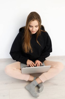 Ciddi derecede serbest çalışan, süveterli bir kadın dizüstü bilgisayarla yerde oturuyor, konsept online eğitim, evden çalışma, beyaz arka plan, kopyalama alanı