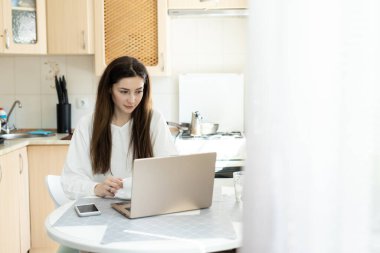 Mutfakta dizüstü bilgisayarı olan kız. Öğrenci sanal öğretmenle çevrimiçi çalışıyor ve yeni dersler öğreniyor. Uzaktan eğitim e-öğrenme kavramı