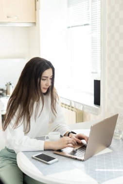 Öğrenci evde online dersler izleyerek para kazanıyor. Mutfakta dizüstü bilgisayarı olan genç kız. E-öğrenim eğitim konsepti.