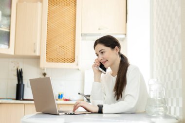 Evde cep telefonuyla gülümseyen bağımsız danışmanlar. Evdeki serbest çalışan genç kız metin yazarı. Uzaktan çalışma ve telefon danışma kavramı