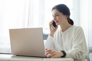 Genç kız uzaktan çalışıyor ve evden telefonla danışmanlık yapıyor. Uzaktan kumandalı yetenekli yönetici dizüstü bilgisayarda e-posta okuyor. Uzaktan çalışma ve telefon danışma kavramı