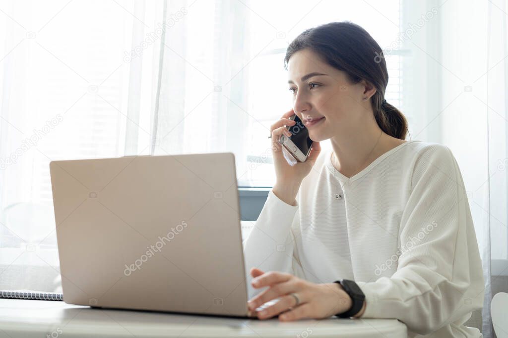 The young girl remote work and consults by phone from home. Talented manager remote working in laptop reading e-mail. Remote working and telephone consultations concept