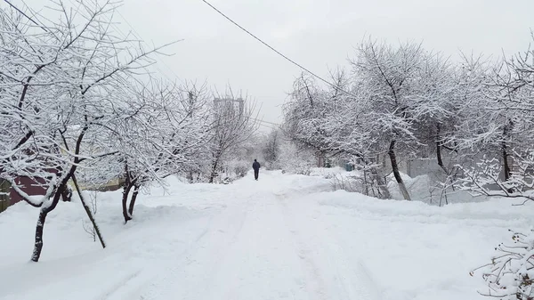 Homem caminha ao longo da estrada nevada no inverno - rua branca — Fotografia de Stock