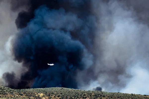 White Aircraft Flying Ahead of the Dense Black Smoke Rising from the Raging Wildfire — Stock Photo, Image