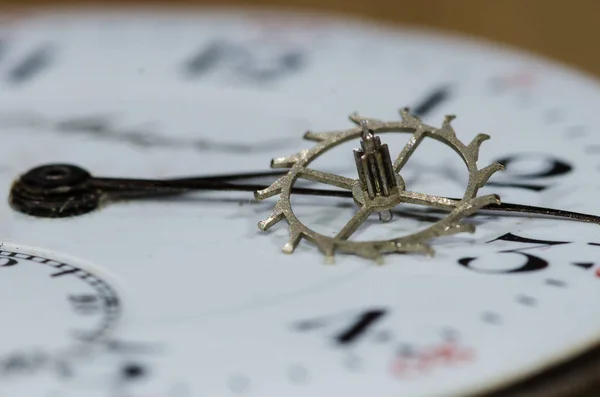 Piezas del reloj: Rueda de escape metálica vintage descansando en la cara del reloj de bolsillo —  Fotos de Stock