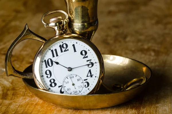 Relógio de bolso dourado vintage descansando em um castiçal de bronze — Fotografia de Stock