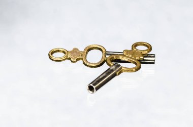 İki antika pirinç cep saatini anahtar üzerinde beyaz yüzey döşeme 