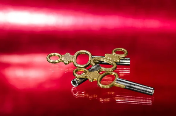 Três chaves antigas do relógio de bolso do bronze que colocam na superfície vermelha — Fotografia de Stock