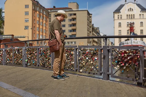 Turisztikai ember megfigyelése lovelocks csatolva egy híd a szeretet korlát, Helsinki, Finnország. — Stock Fotó