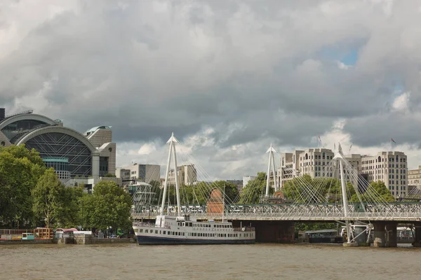 Vista de los Puentes del Jubileo de Oro y la estación Charing Cross desde la orilla sur del río Támesis en Londres en un día nublado de verano . — Foto de Stock