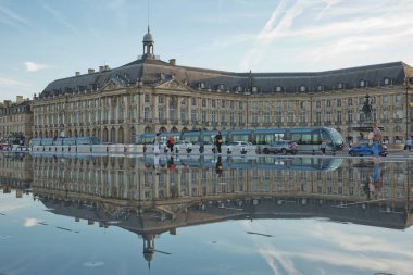 İnsanlar sıcak bir yaz gününde Bordeaux 'daki Place de la Bourse' un önündeki ayna çeşmesinde eğlenir ve ferahlatır.