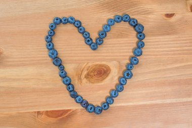 Yaban mersini çilek ahşap arka plan üzerinde bir kalp şeklinde